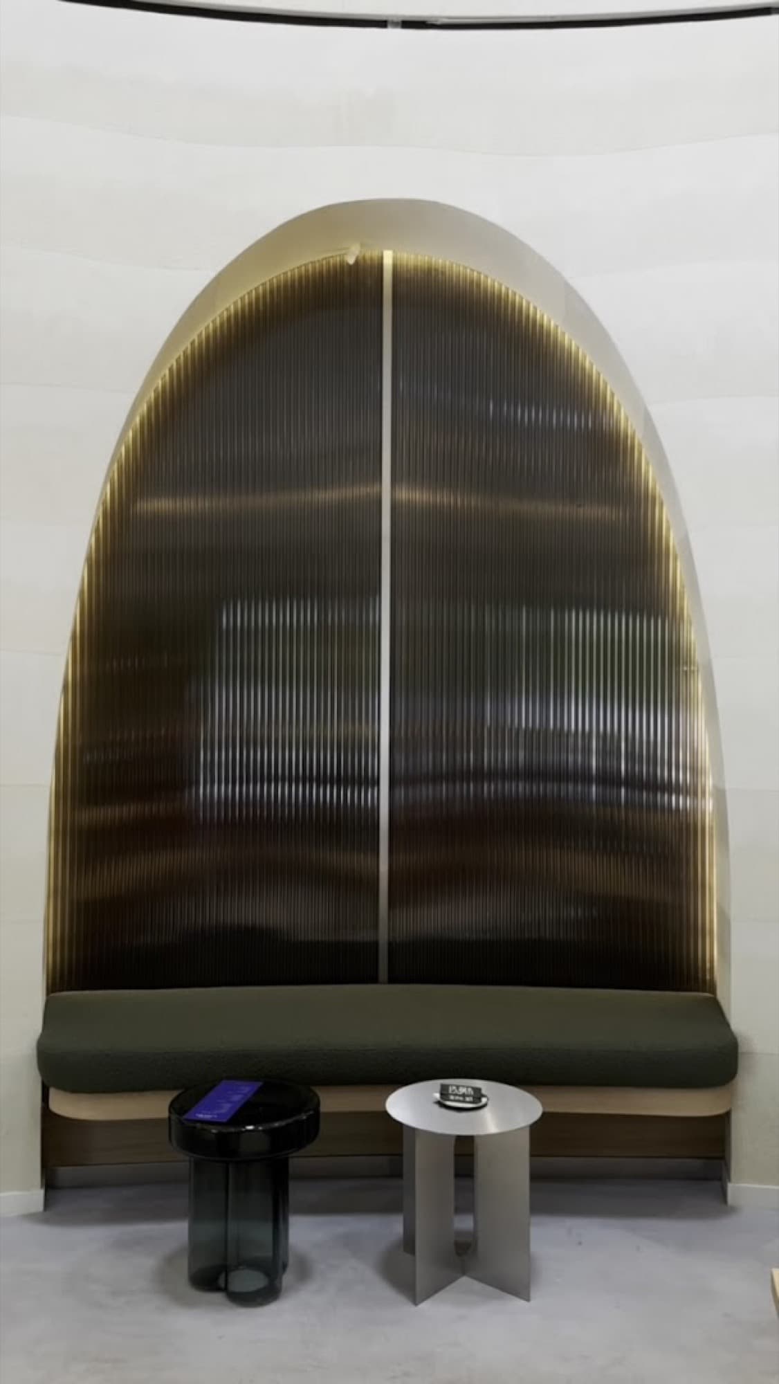 An arched alcove with fluted bronze glass and an olive banquette
